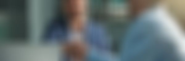 Zwei Geschäftsmänner sitzen am Schreibtisch und geben sich die Hände.