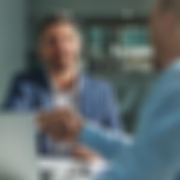 Zwei Geschäftsmänner sitzen am Schreibtisch und geben sich die Hände.