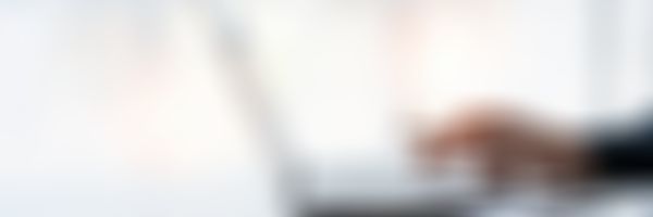 Männliches Hand mit Kugelschreiber in der Hand tippt auf Laptop.