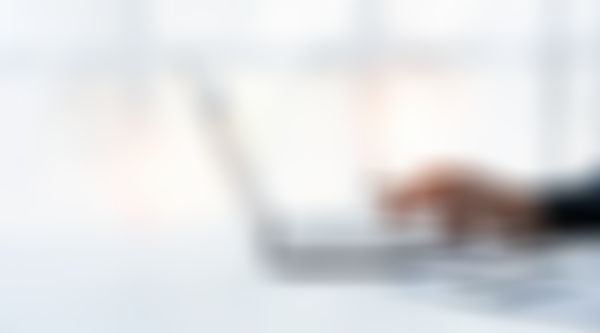 Männliches Hand mit Kugelschreiber in der Hand tippt auf Laptop.