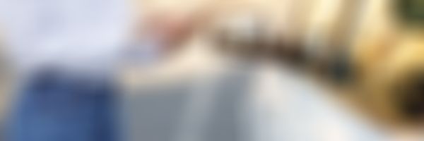 Frau steht mit Handy vor weißem Auto.