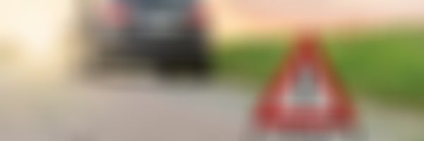 Frau lehnt an Auto, Autopanne, Pannendreieck.