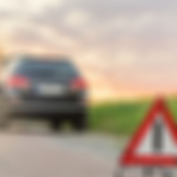 Frau lehnt an Auto, Autopanne, Pannendreieck.