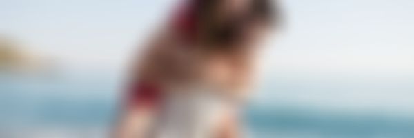 Mann trägt Frau auf dem Rücken den Strand entlang