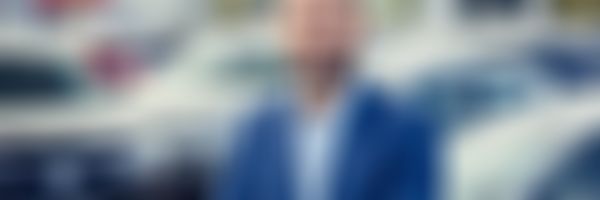 Autohausverkäufer steht vor Autos.