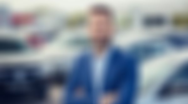 Autohausverkäufer steht vor Autos.