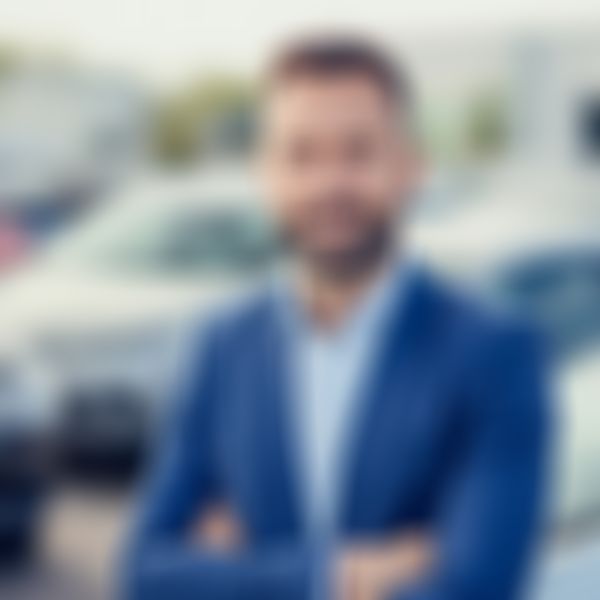 Autohausverkäufer steht vor Autos.