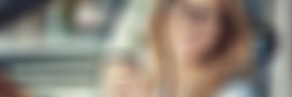 Kfz-Haftpflicht-Versicherung - Frau im Auto bei offenem Fenster und einem Kaffee in der Hand