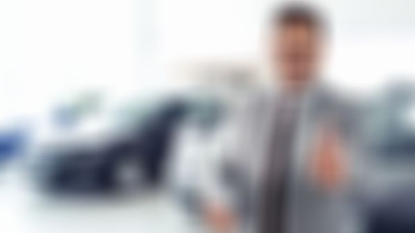 Autohausverkäufer lächelt und zeigt den Daumen nach oben.