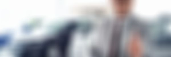 Autohausverkäufer lächelt und zeigt den Daumen nach oben.