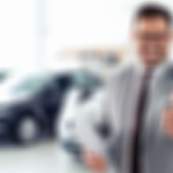 Autohausverkäufer lächelt und zeigt den Daumen nach oben.