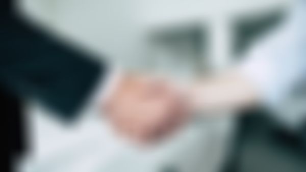 Handschlag; im Hintergrund ein weißes Auto.