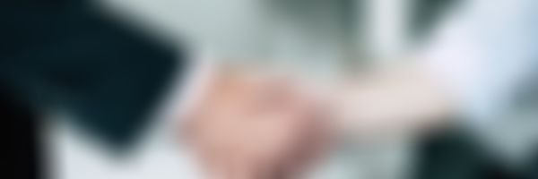 Handschlag; im Hintergrund ein weißes Auto.