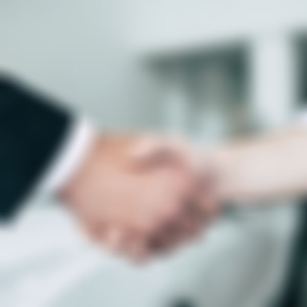 Handschlag; im Hintergrund ein weißes Auto.