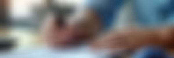 Person sitzt am Schreibtisch und bearbeitet Unterlagen
