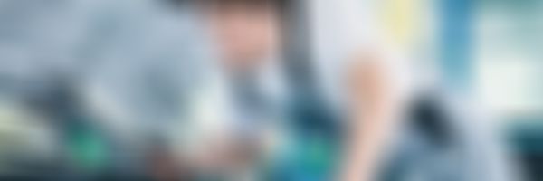 Mechaniker lehnt sich mit Taschenlampe über die Motorhaube