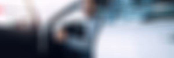 Teilkasko-Versicherung - Mann mit Brille sitzt lächelnd auf Fahrersitz