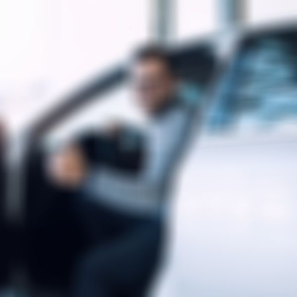 Teilkasko-Versicherung - Mann mit Brille sitzt lächelnd auf Fahrersitz