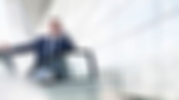 Mann im Anzug steht bei der offenen Autotür und telefoniert