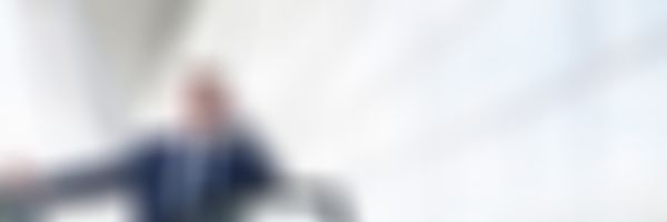 Mann im Anzug steht bei der offenen Autotür und telefoniert