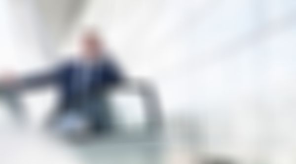 Mann im Anzug steht bei der offenen Autotür und telefoniert