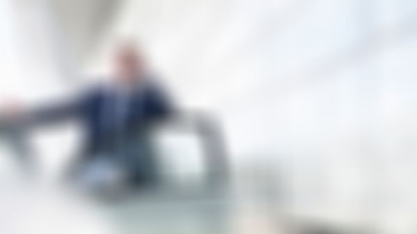 Mann im Anzug steht bei der offenen Autotür und telefoniert