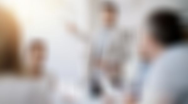 Mann trägt vor Gruppe vor und zeigt auf Flipchart.