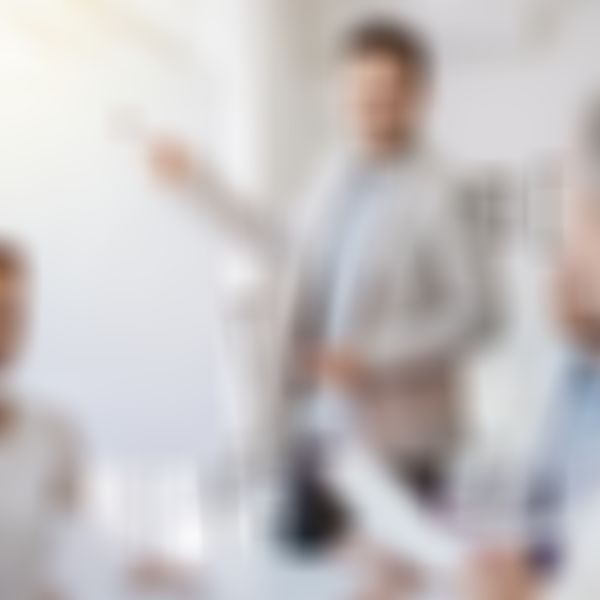 Mann trägt vor Gruppe vor und zeigt auf Flipchart.