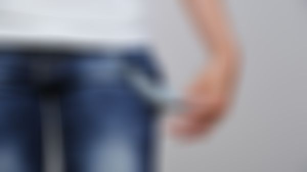 Frau greift sich in die Hosentasche und zieht leere Innentasche heraus.