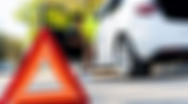 Warndreieck im Vordergrund, Frau steigt im Hintergrund aus weißem Auto aus