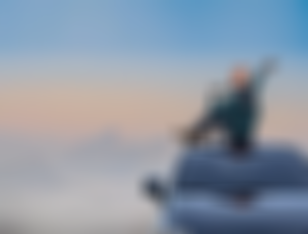 GARANTA Image Sujet - Campende Frau sitzt auf ihrem Autodach und betrachtet das Bergpanorama