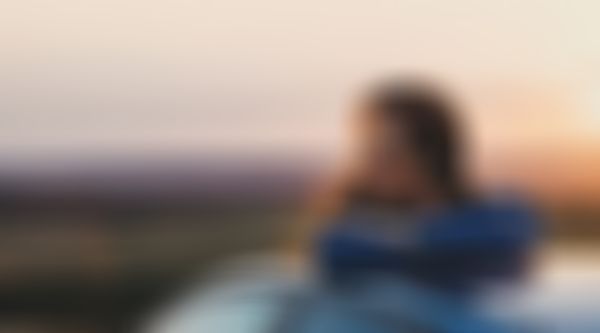 GARANTA Image Sujet - Campende Frau sitzt auf ihrem Autodach und betrachtet das Bergpanorama