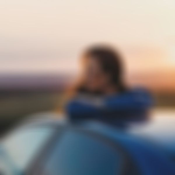 GARANTA Image Sujet - Campende Frau sitzt auf ihrem Autodach und betrachtet das Bergpanorama