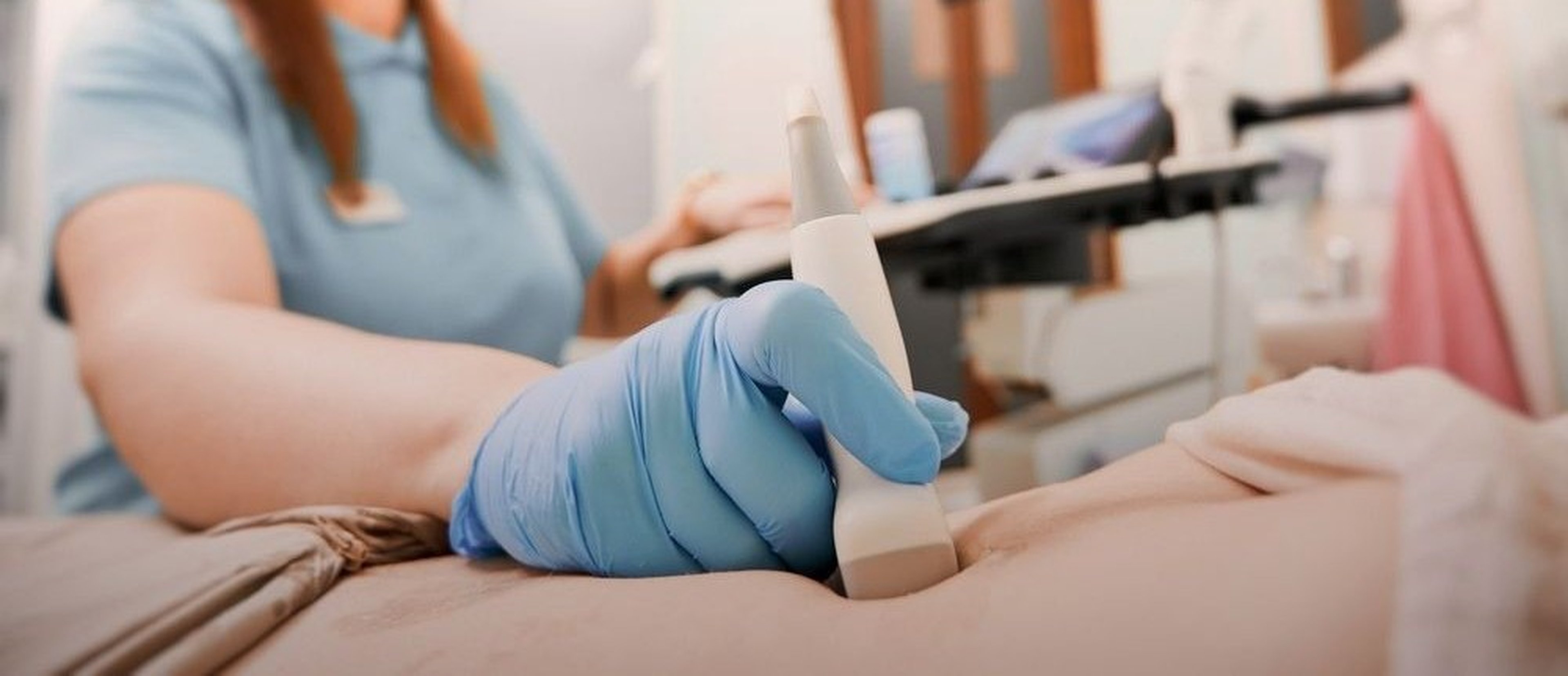 Female doctor moving transducer on patient abdomen