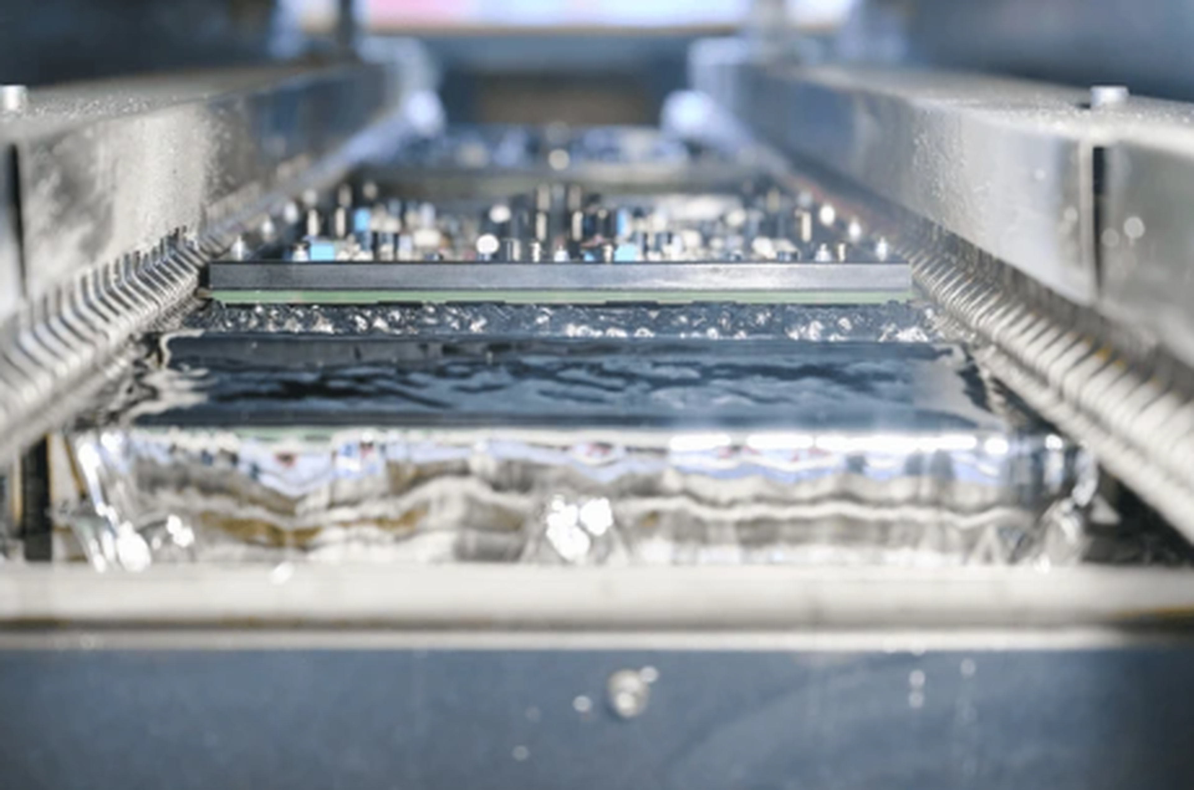Close-up of industrial machine parts with metallic components and water. Focus on reflective surfaces and alternating textures.
