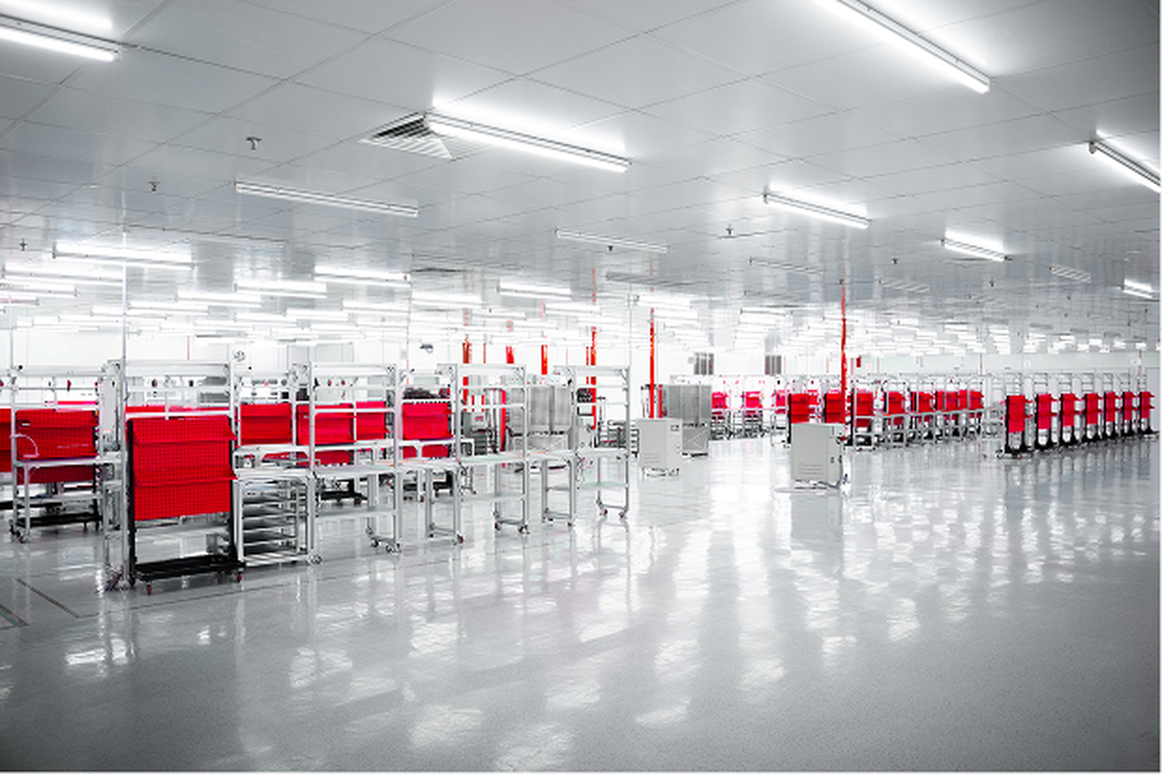 Brightly lit, large industrial space featuring orderly rows of red and silver racks and highly reflective floors, illustrating a clean and efficient manufacturing environment.
