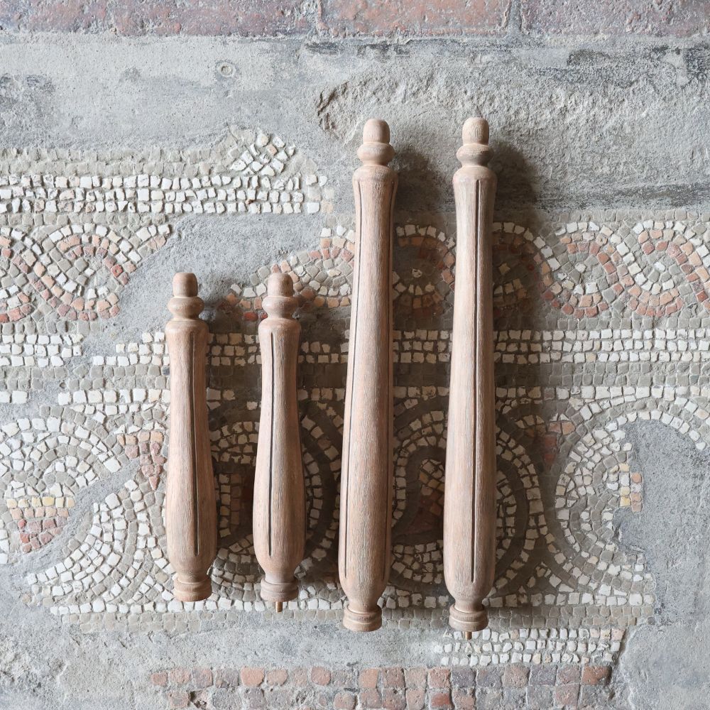 Four wooden table legs on a textured mosaic surface with intricate patterns in the background.