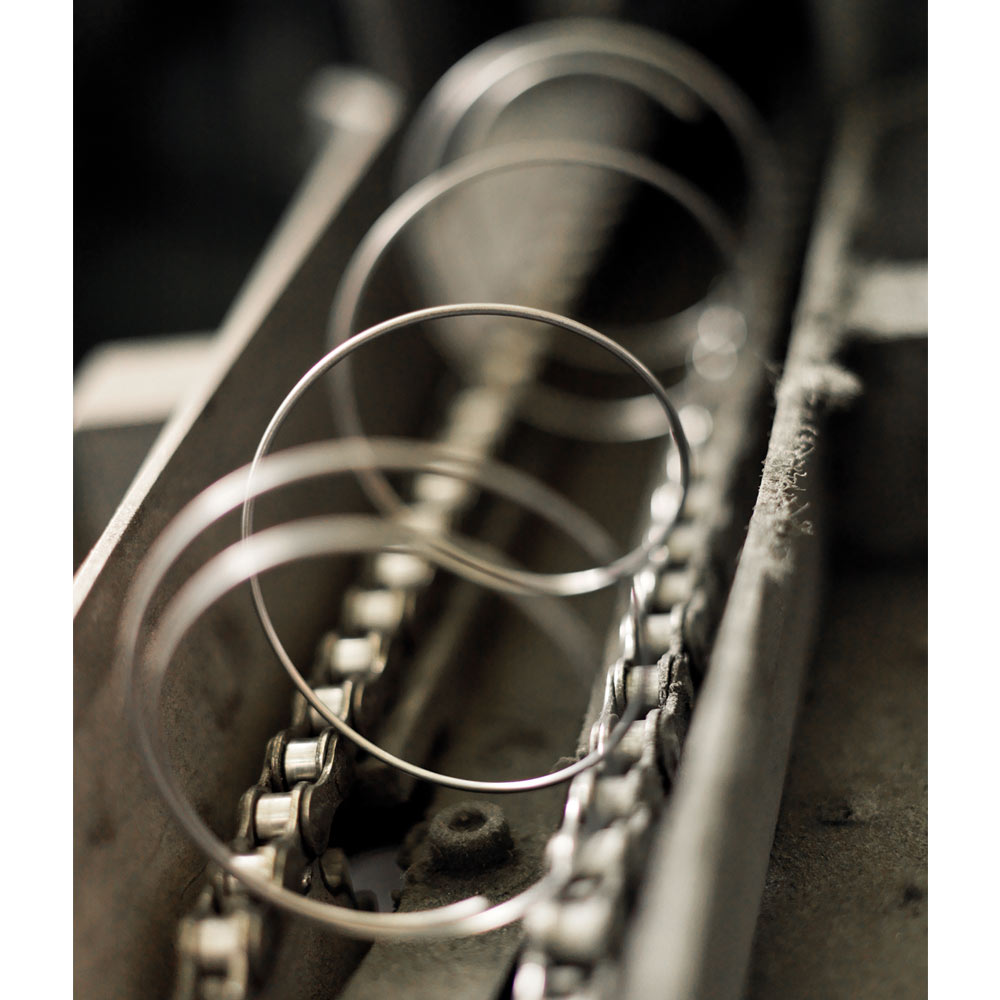 Close-up of metal rings aligned on a conveyor chain in an industrial setting, with a focus on texture and depth.