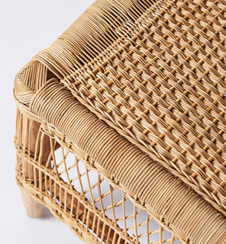 Close-up of a woven rattan chair corner, showcasing intricate weaving and natural texture on a light background.