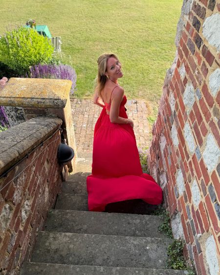 Georgia, Founder of French Bedroom, in a red dress descending stone steps on Glyndebourne's grounds