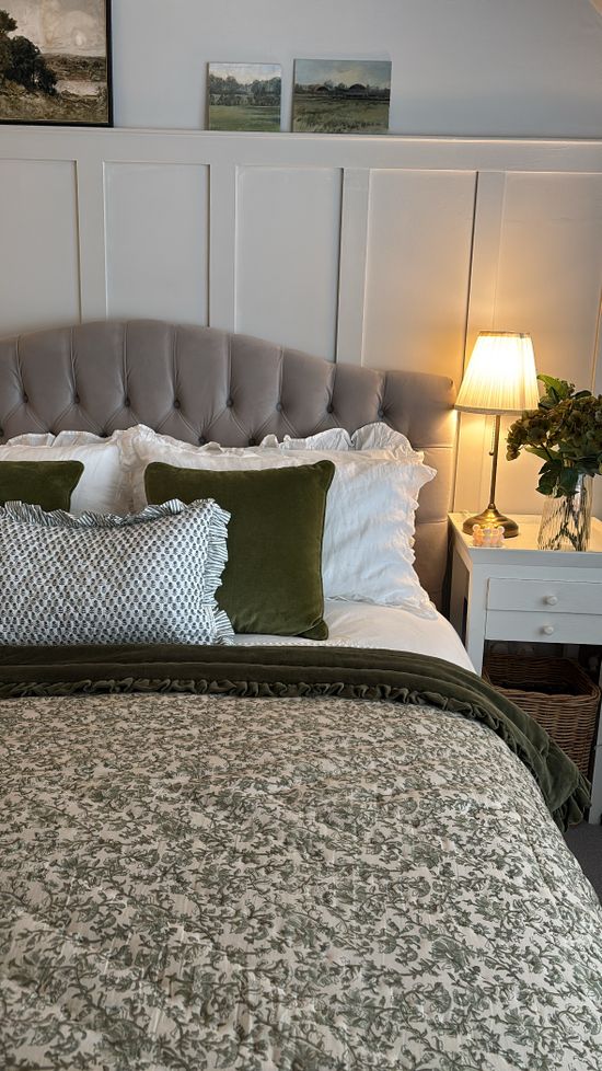 Grey Bed with green velvet throw, green velvet cushion and white and green frilly cushion