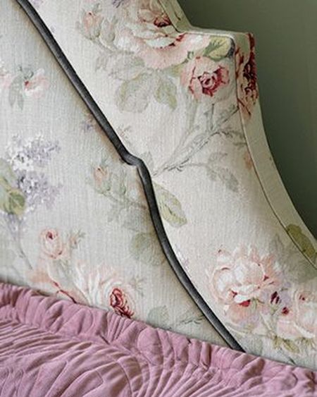 Floral-patterned upholstered headboard with pink and green tones, paired with a textured pink bedspread.