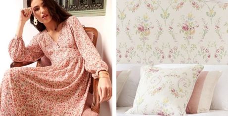 Woman in a floral dress sits on a chair; right side shows a bed with floral pillows and headboard.