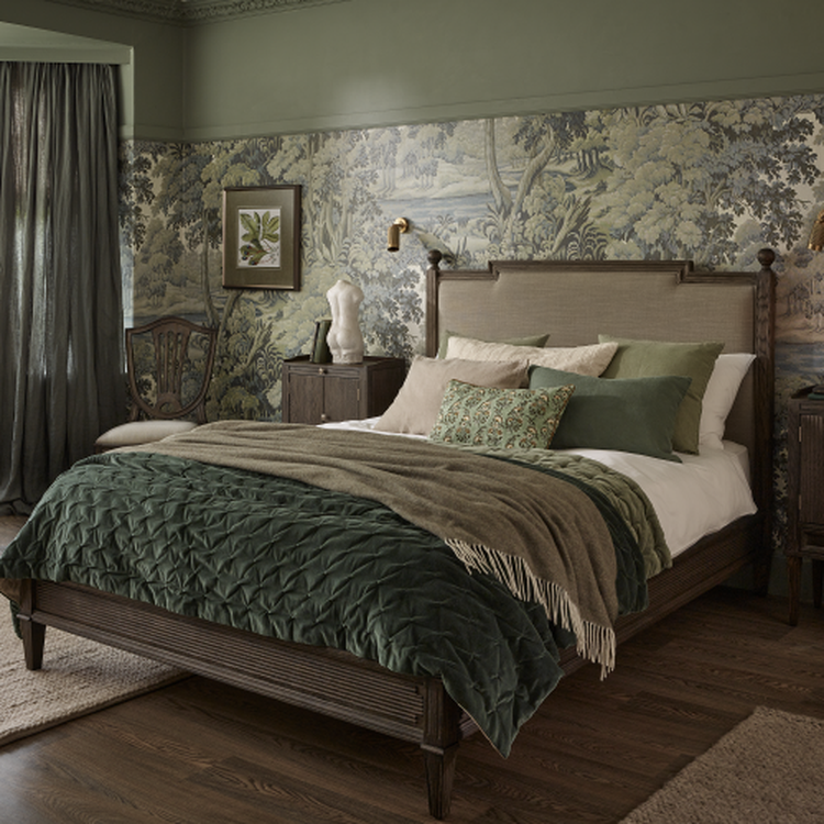 Cosy bedroom with green-themed decor, featuring a wooden bed, patterned wallpaper, and a mix of cushions and throws.