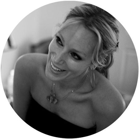 Smiling woman with long hair, wearing hoop earrings and a strapless top, captured in black and white.