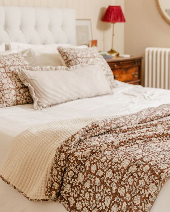 Neutral Bed With Brown Flower Blanket And long Stripe Cushion