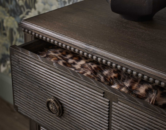 A partially open dark wooden drawer with a decorative front.