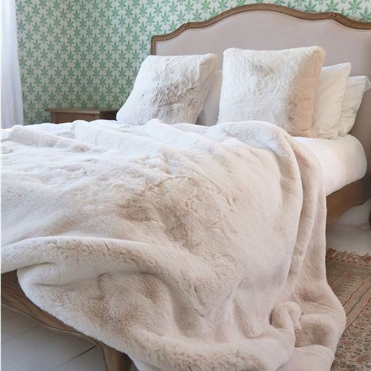 Cozy bedroom with a wooden bed, fluffy white pillows, and a soft beige blanket. Green patterned wallpaper adds a touch of elegance.