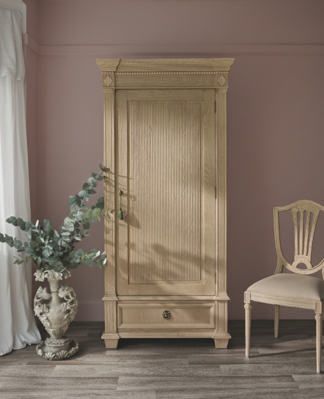 Elegant wooden wardrobe in a room with pink walls, alongside a potted plant and a classic wooden chair on a wooden floor.