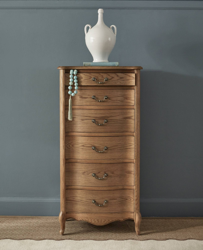 Tall Boy wooden chest of drawers with ornate handles, topped with a white ceramic vase.